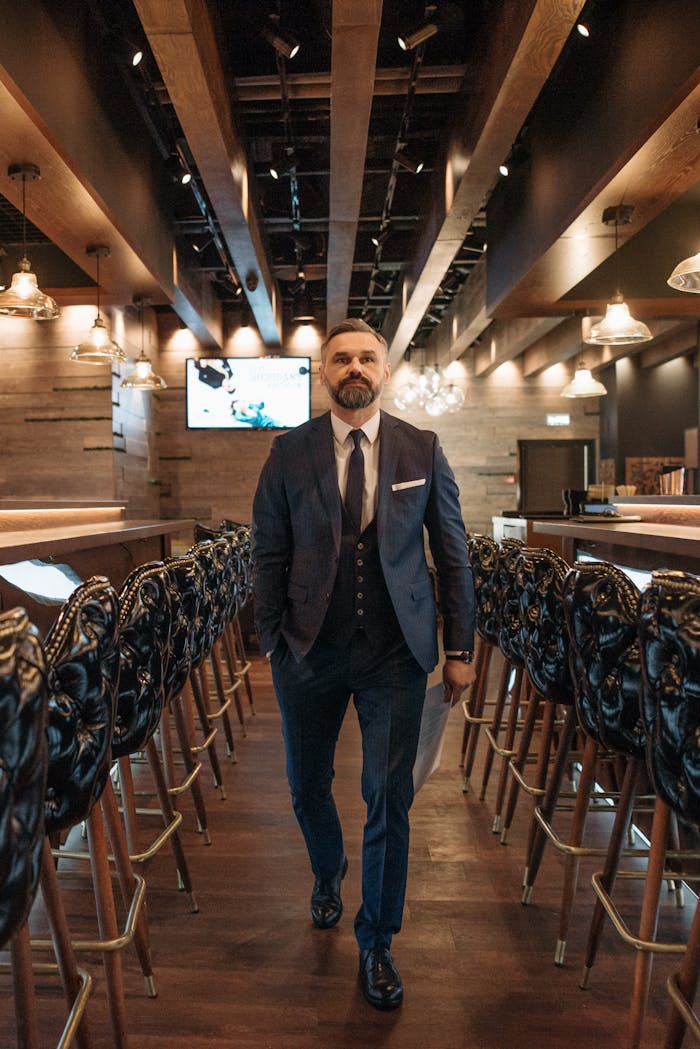 Well-dressed man confidently walking through an elegant bar interior.